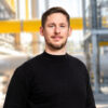 junger Mann mit dunklem Pulli schaut freundlich in die Kamera